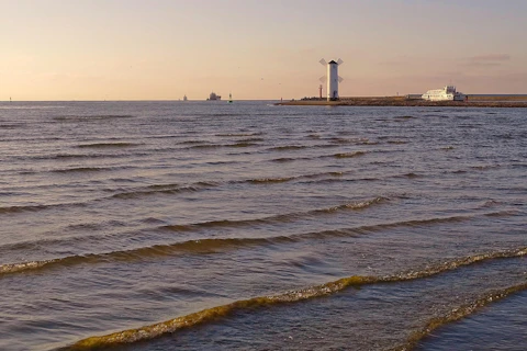 Morze Bałtyckie z widocznymi w tle statkami i latarnią morską.